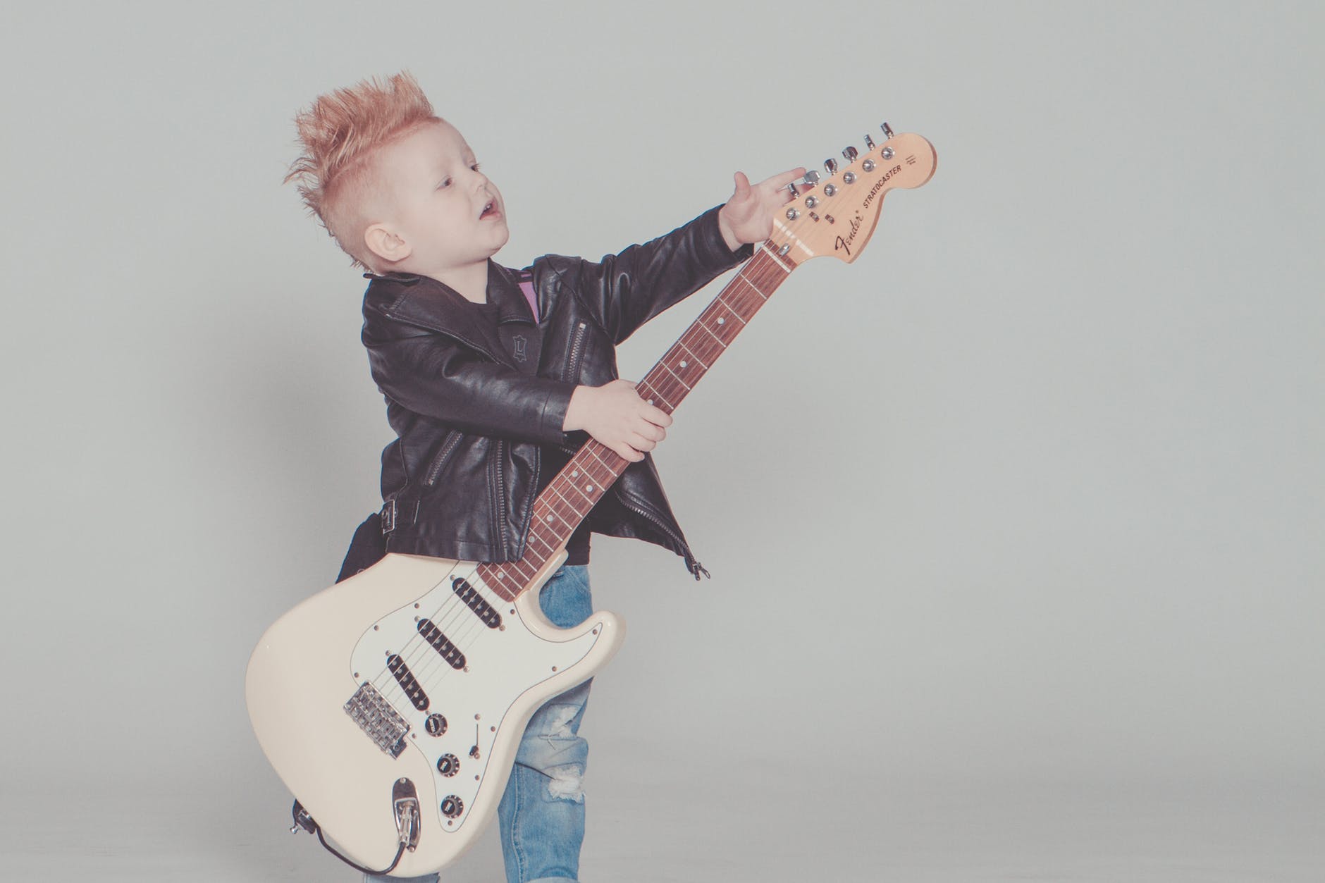 boy wearing black jacket holding electric guitar