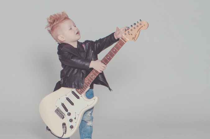 boy wearing black jacket holding electric guitar