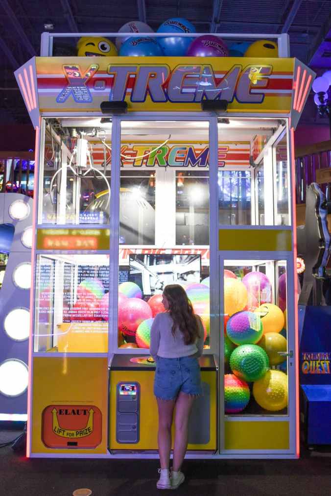 woman standing in front of x treme arcade machine